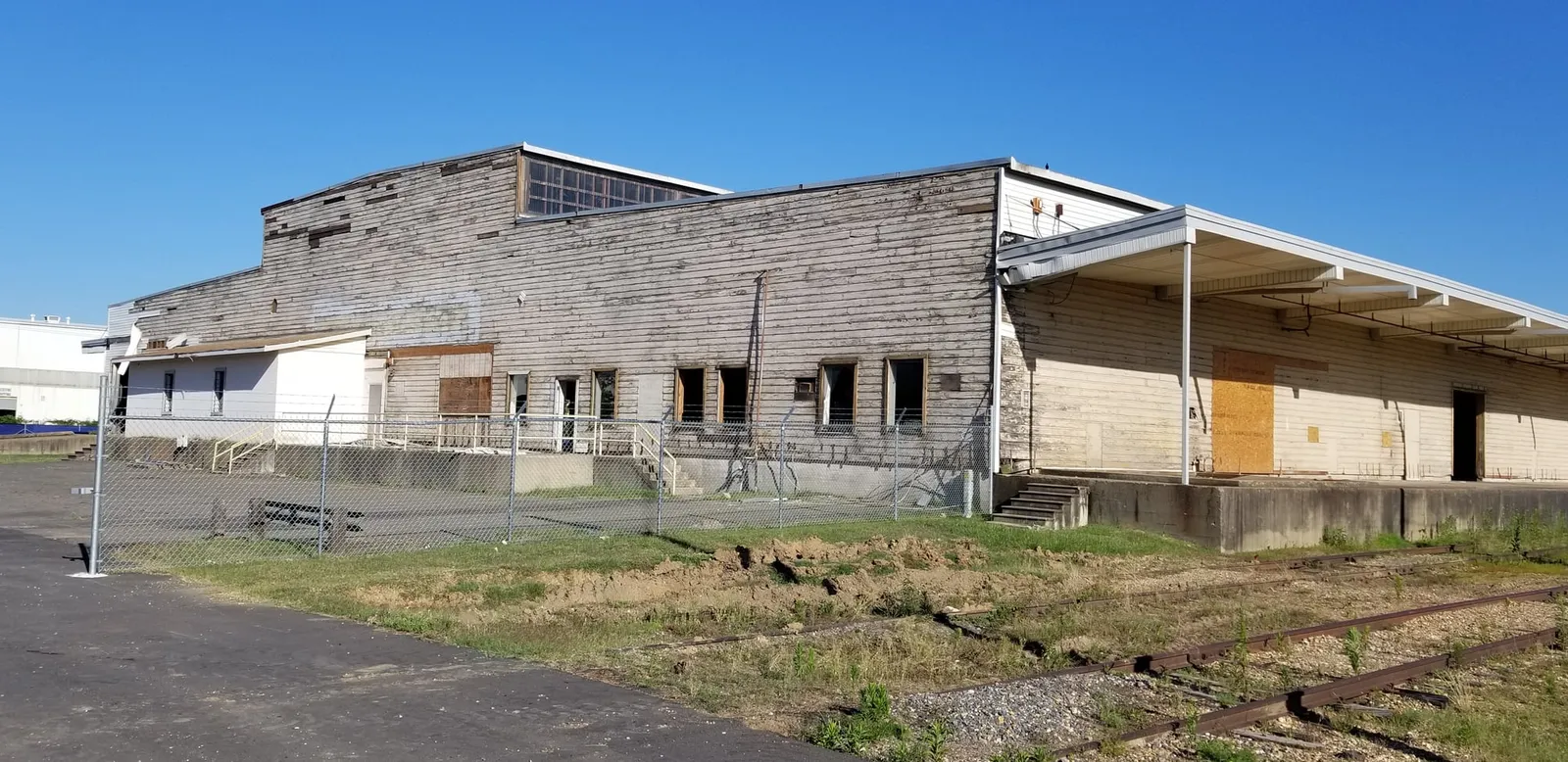 Before the renovation: weathered siding, boarded-up windows and an overgrown loading dock.