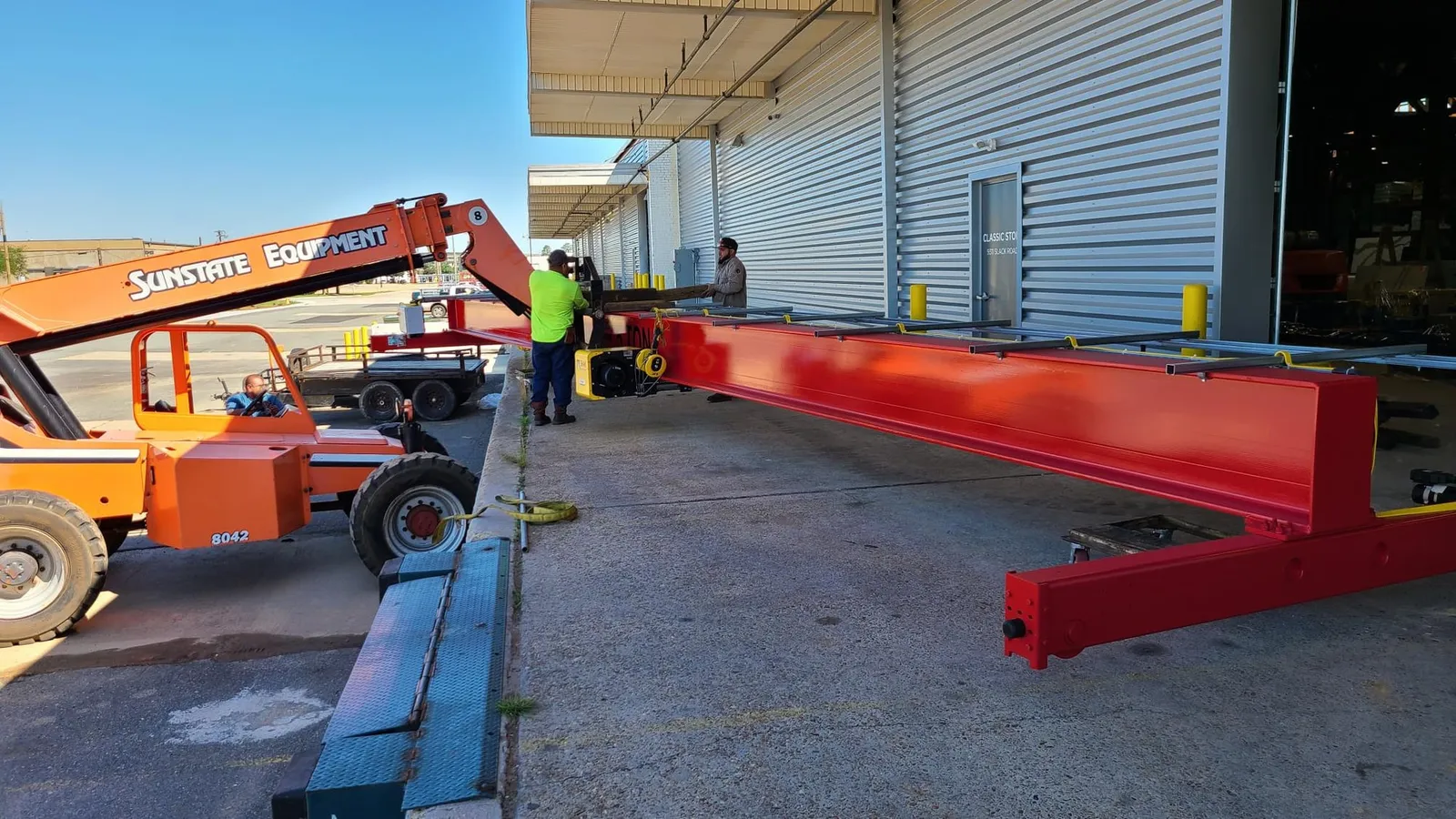 The saw’s long red bridge beam is unloaded at the dock.