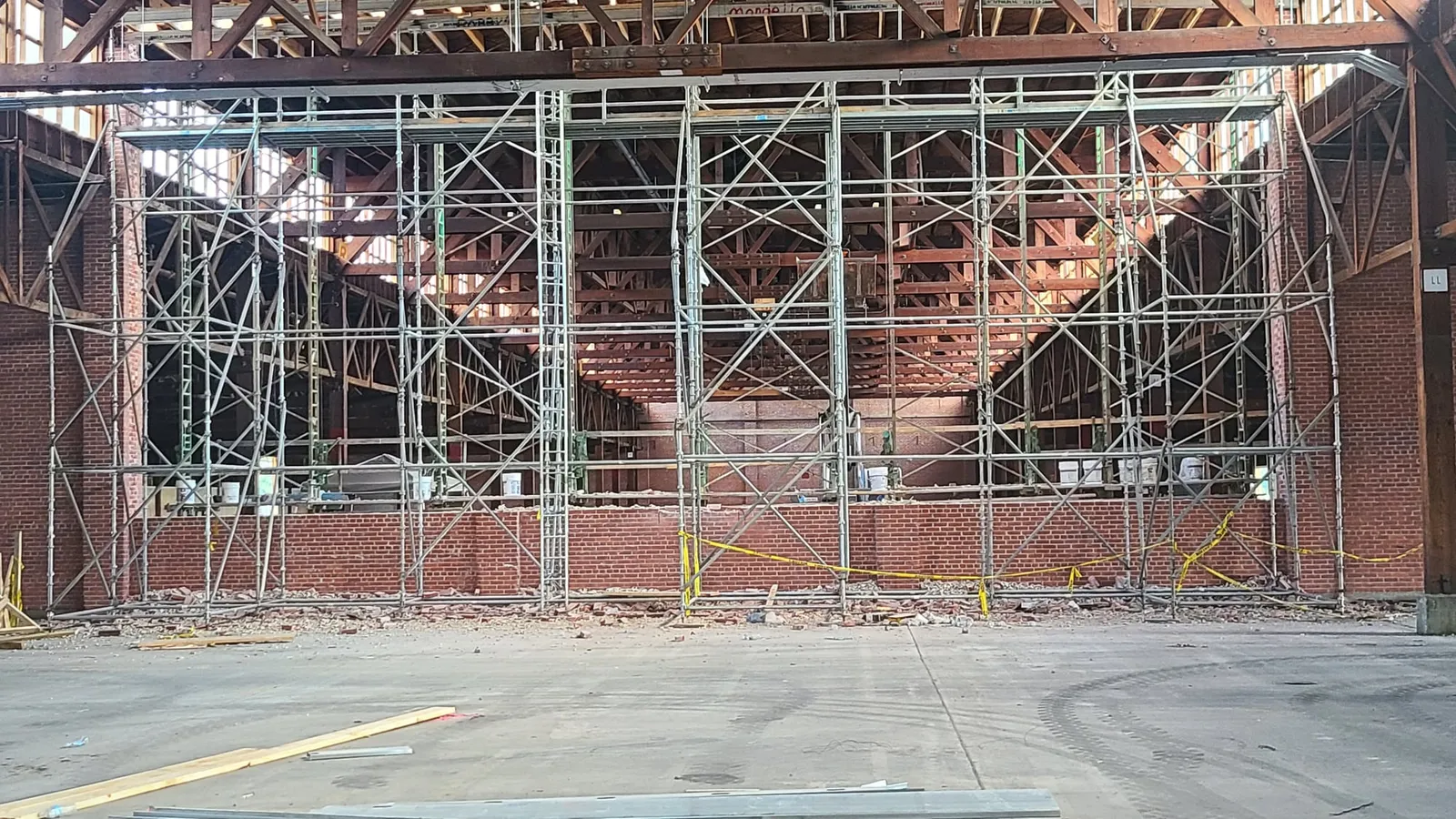 Scaffolding along the exposed brick wall under the timber trusses.