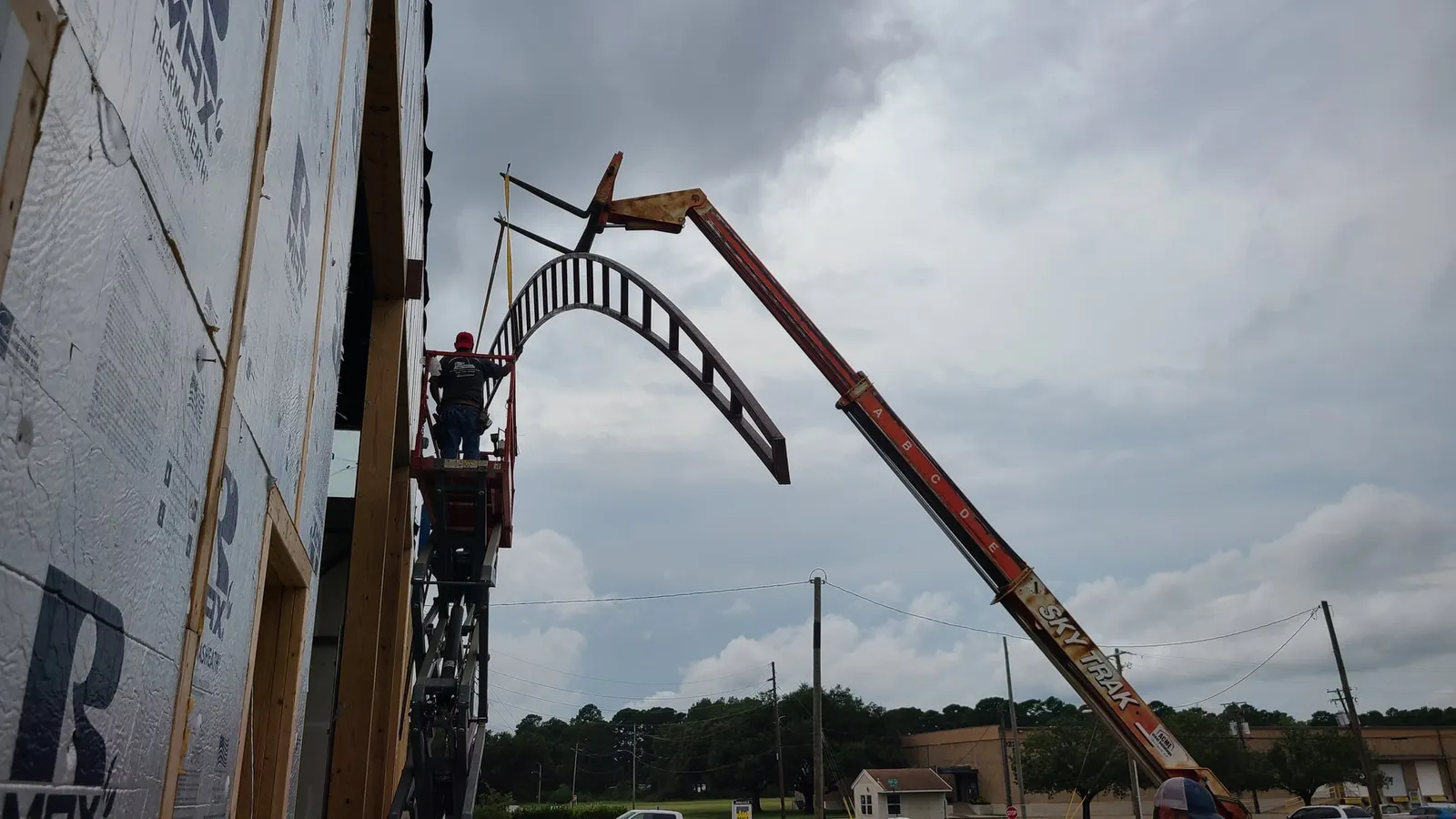 A crane lifts a curved steel beam for the new entrance arch.