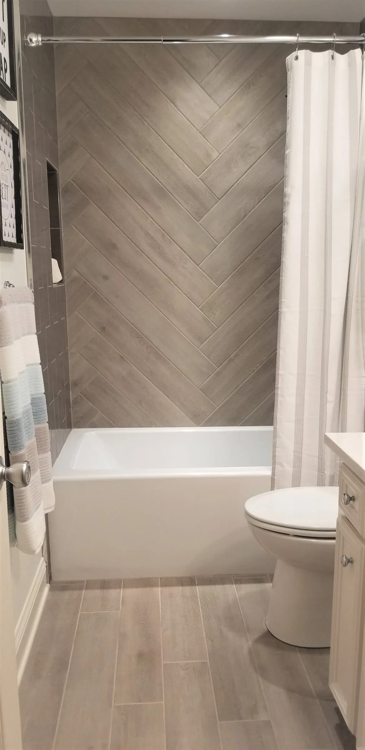 Tub and shower surround in gray herringbone tile.
