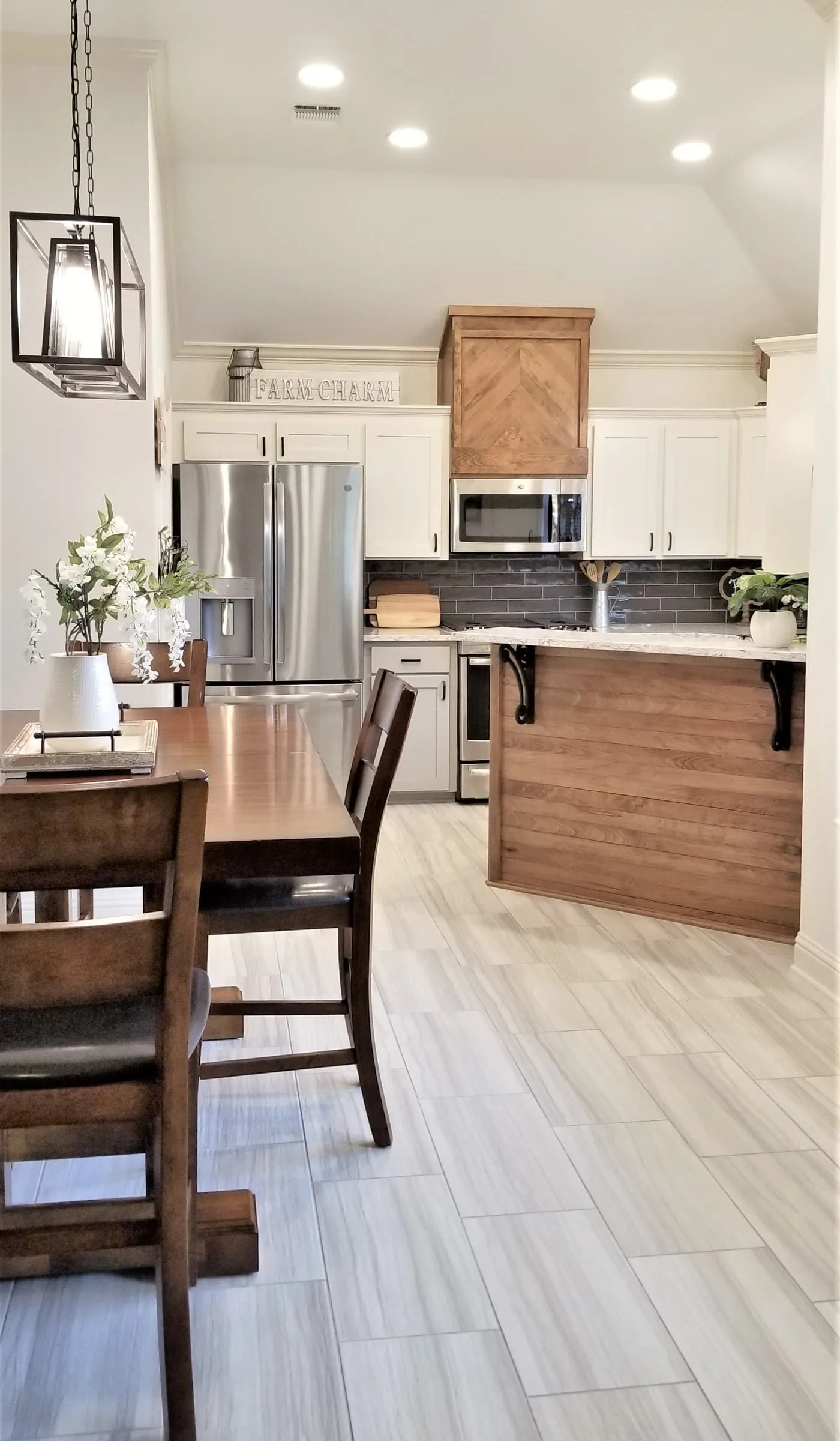 Country kitchen with white cabinets, a wood-clad range hood and a wood island, seen from the dining area.