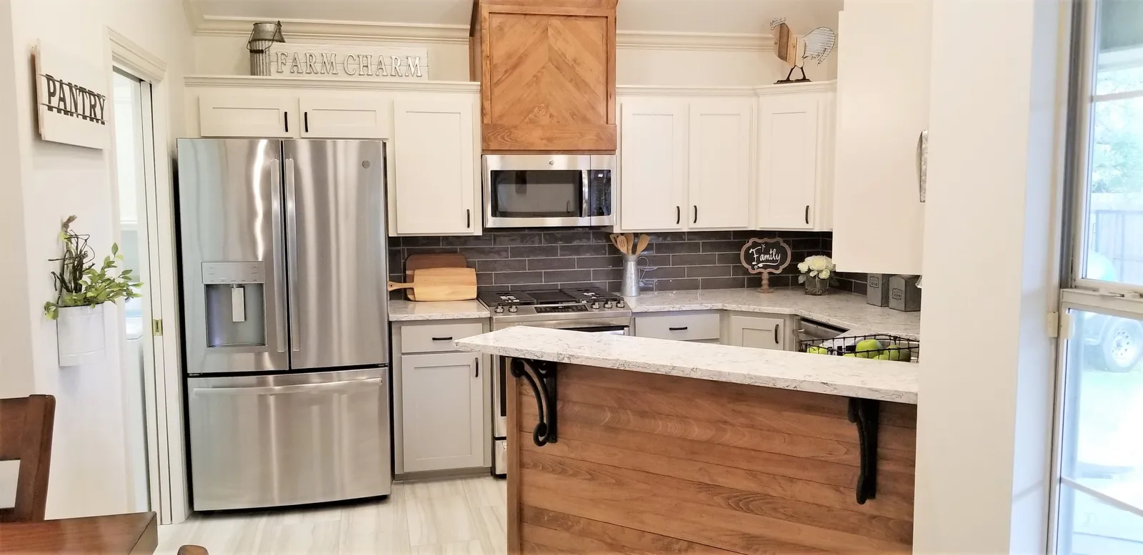 Kitchen with white cabinets, a black tile backsplash and a wood-paneled island.