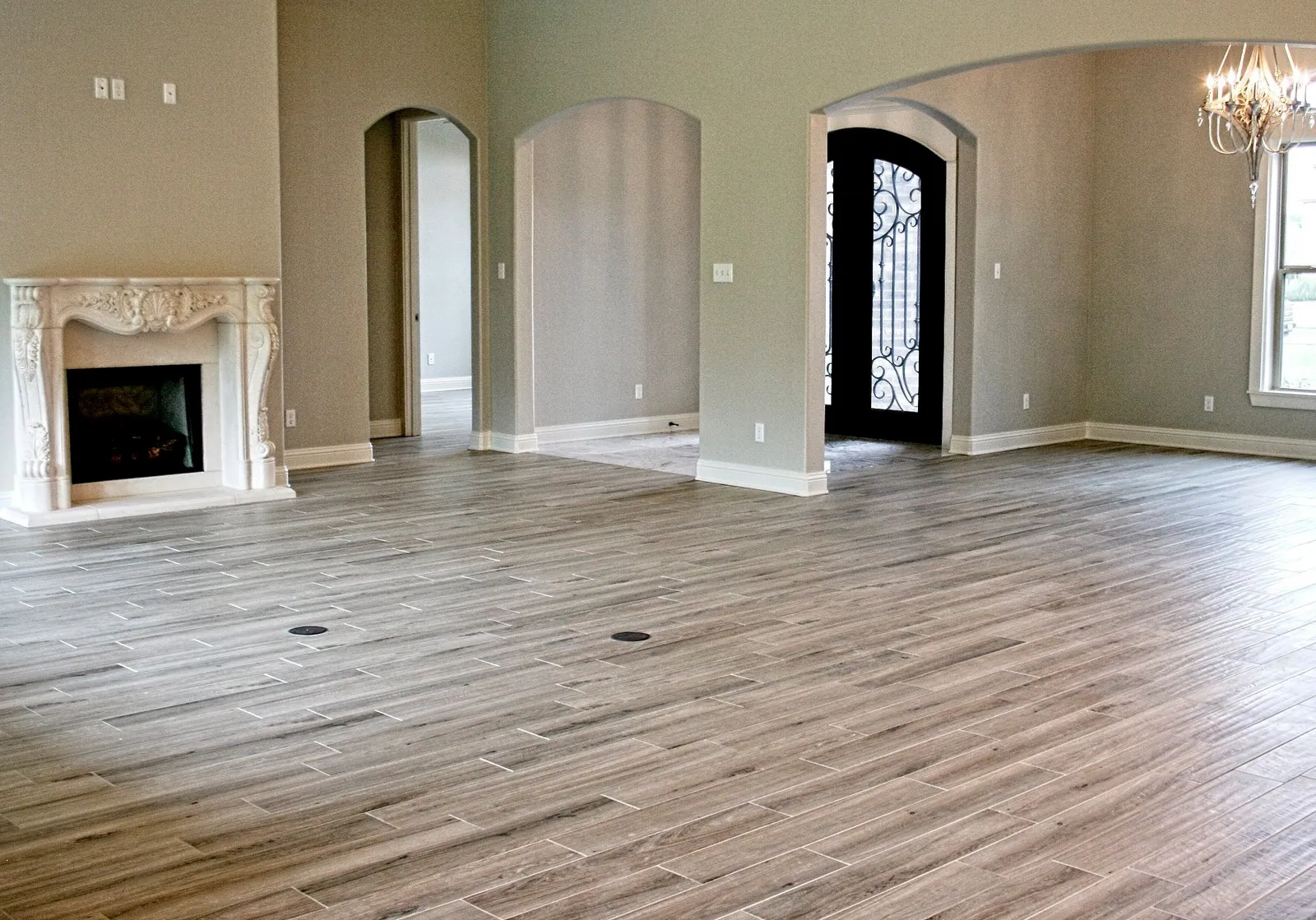 Large living room with wood-look porcelain tile floors and a carved stone fireplace.