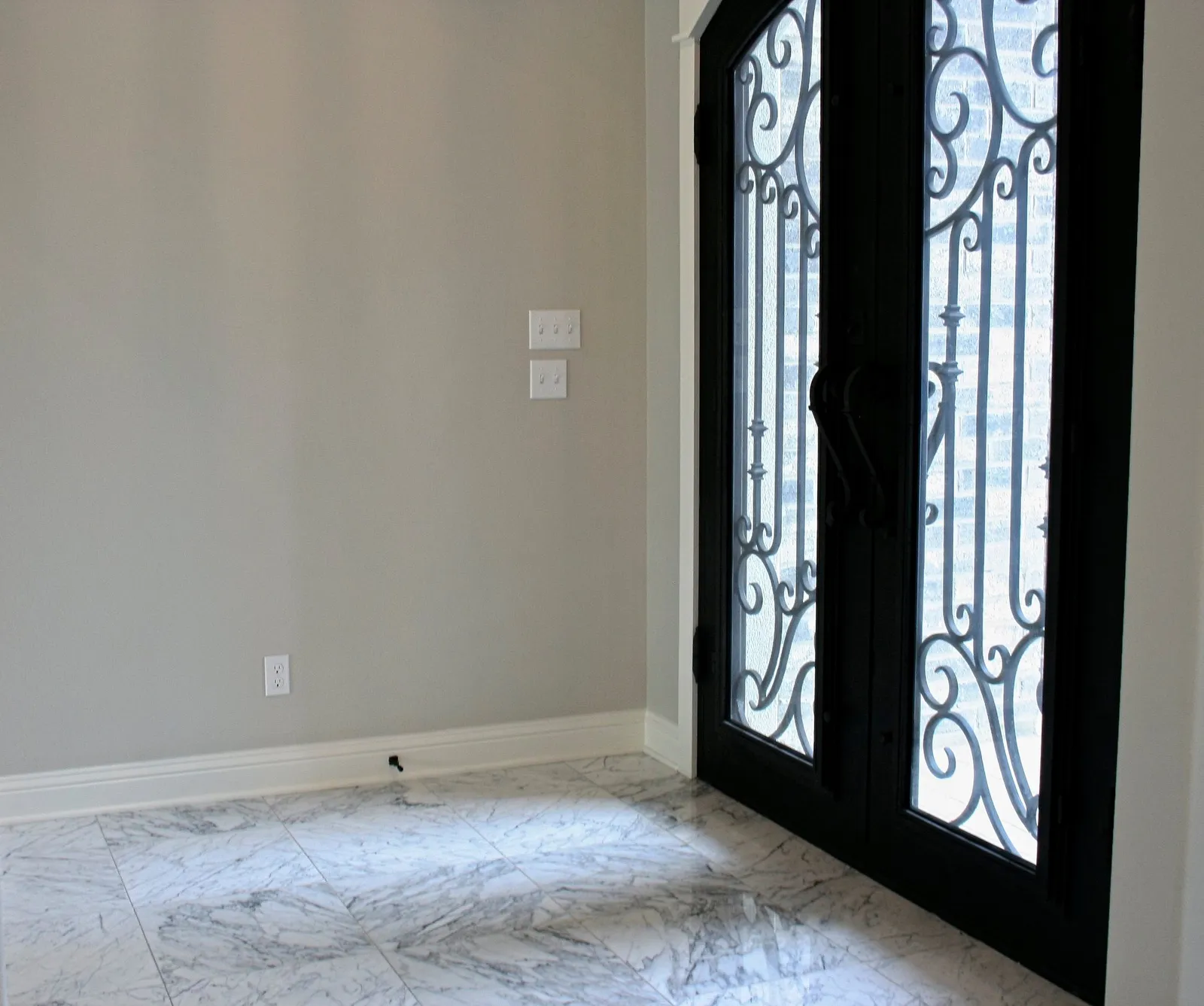 Arched wrought iron front doors above a tile floor.