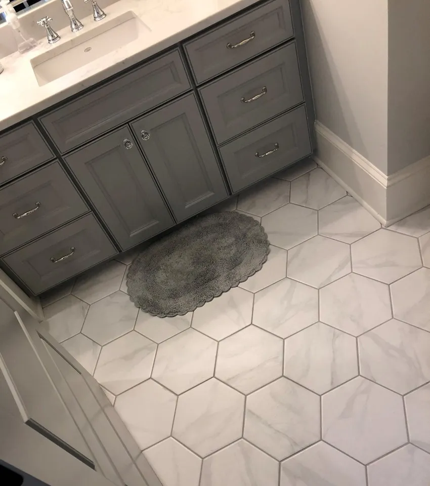 Gray vanity on a white hexagon tile floor.
