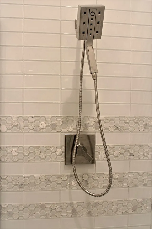 Shower wall in white tile with a decorative accent band.