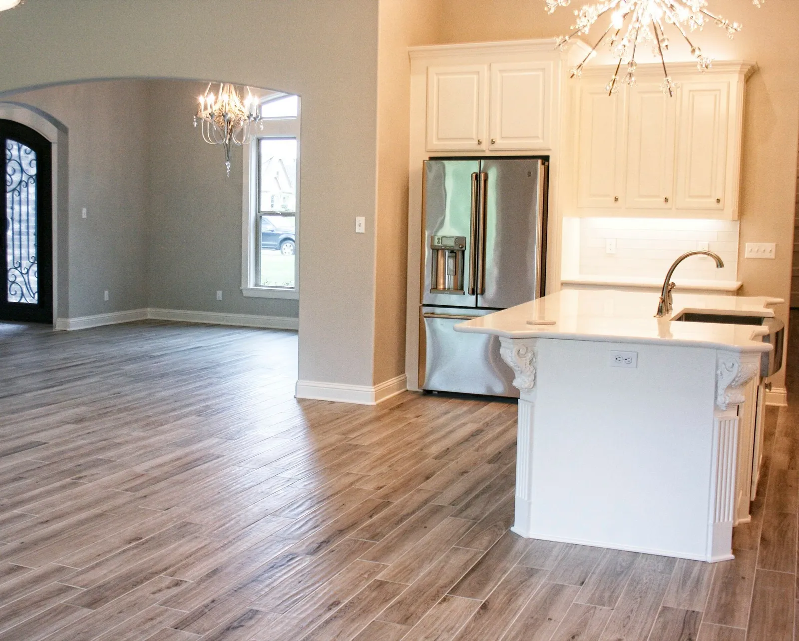 Kitchen island and wood-look porcelain floor flowing into the open living area.