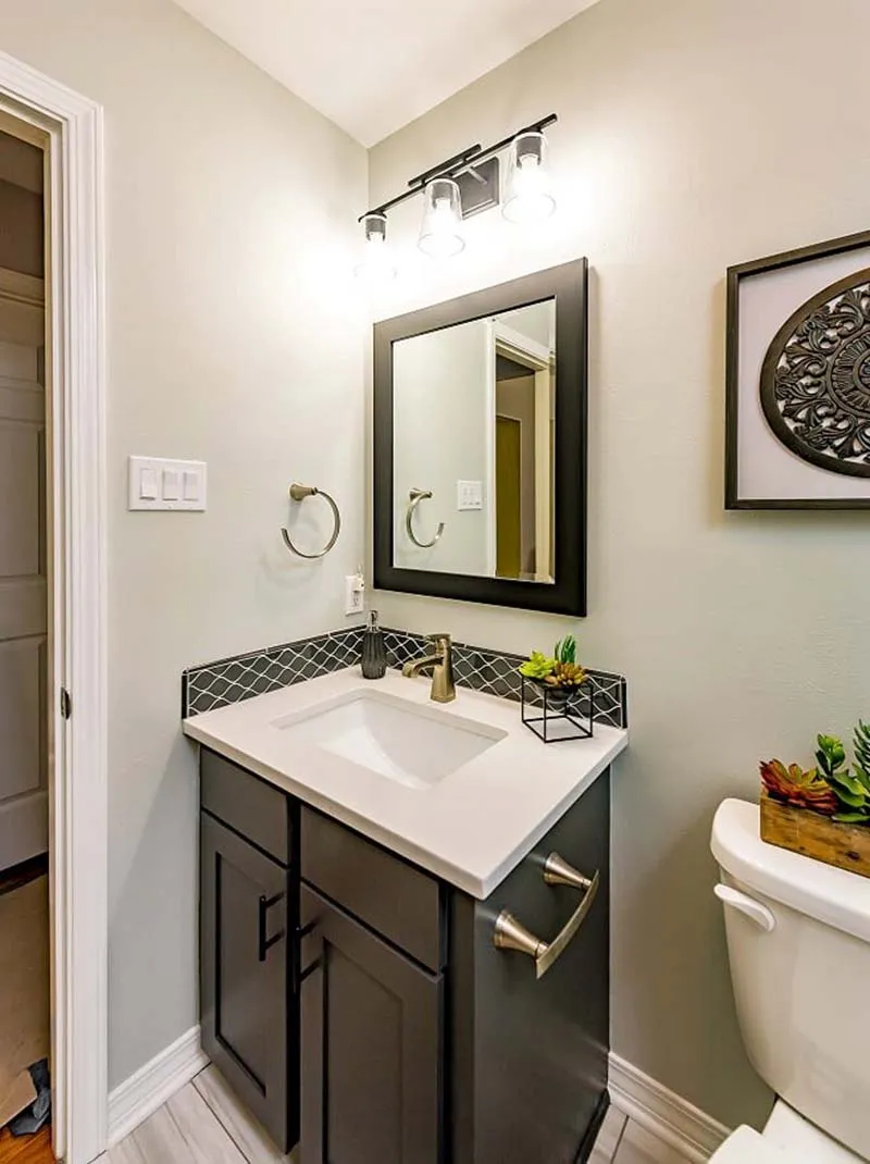 Bathroom with a dark vanity and a black-framed mirror.