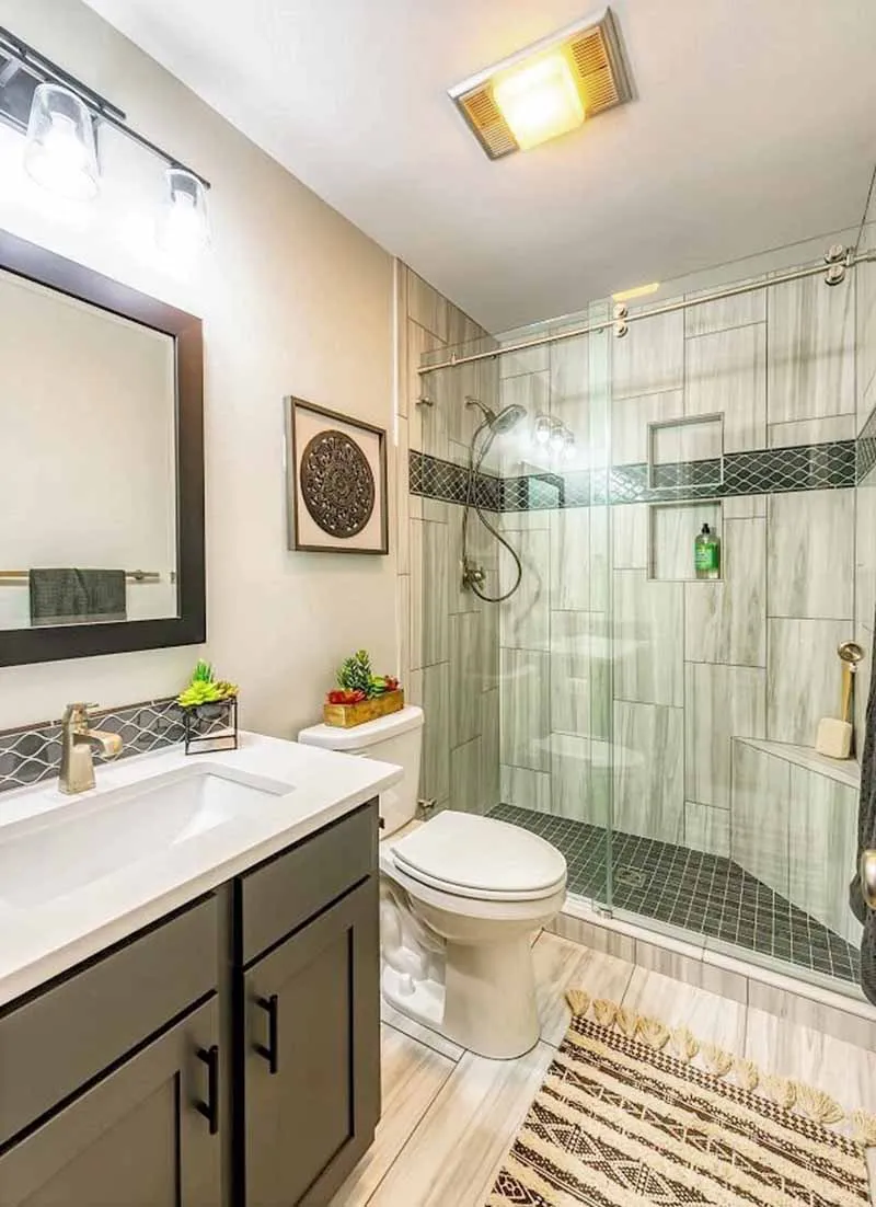 Walk-in shower in tall white tile with a dark mosaic accent stripe.