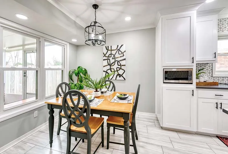 Breakfast nook with a wood table next to the white kitchen.