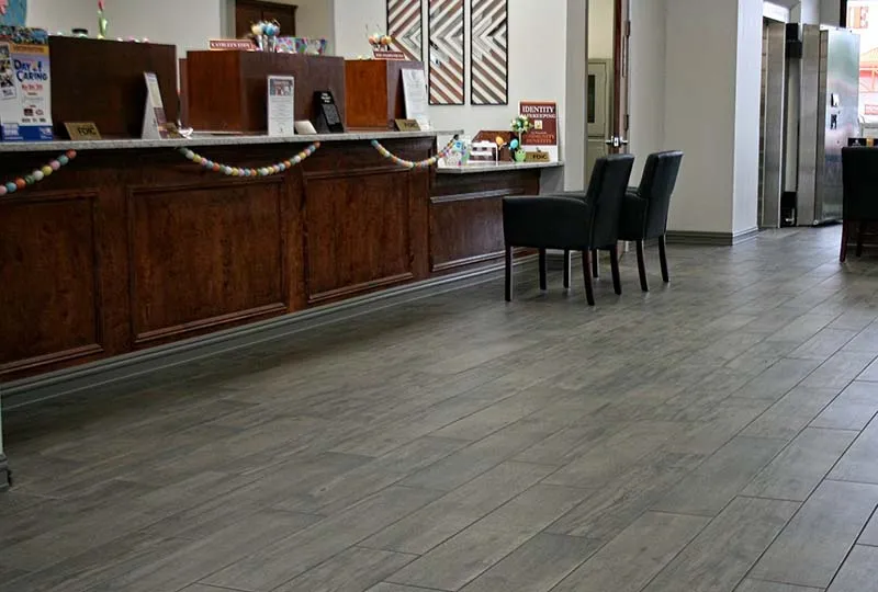 Bank teller line with gray wood-look plank tile floors.
