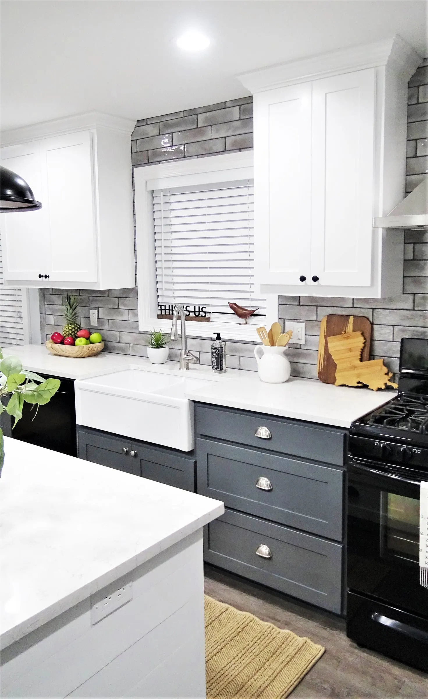 Farmhouse sink and dark gray cabinets below a window.