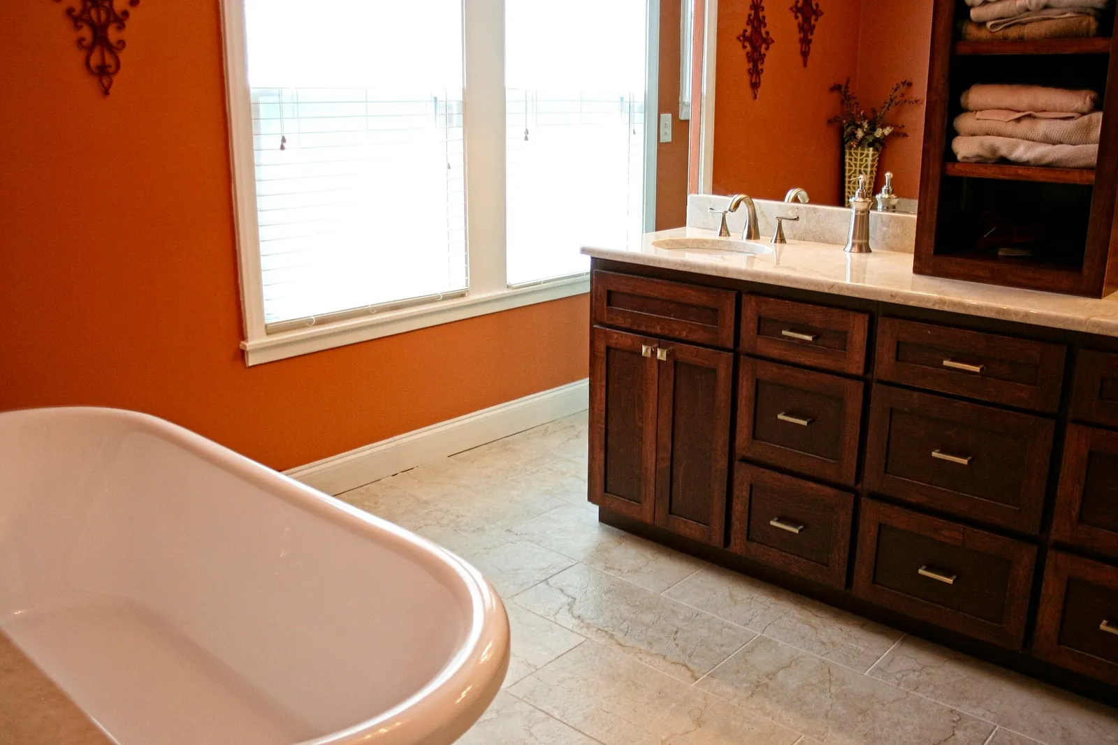 Bathroom with a cherry vanity and a clawfoot tub against a burnt orange wall.