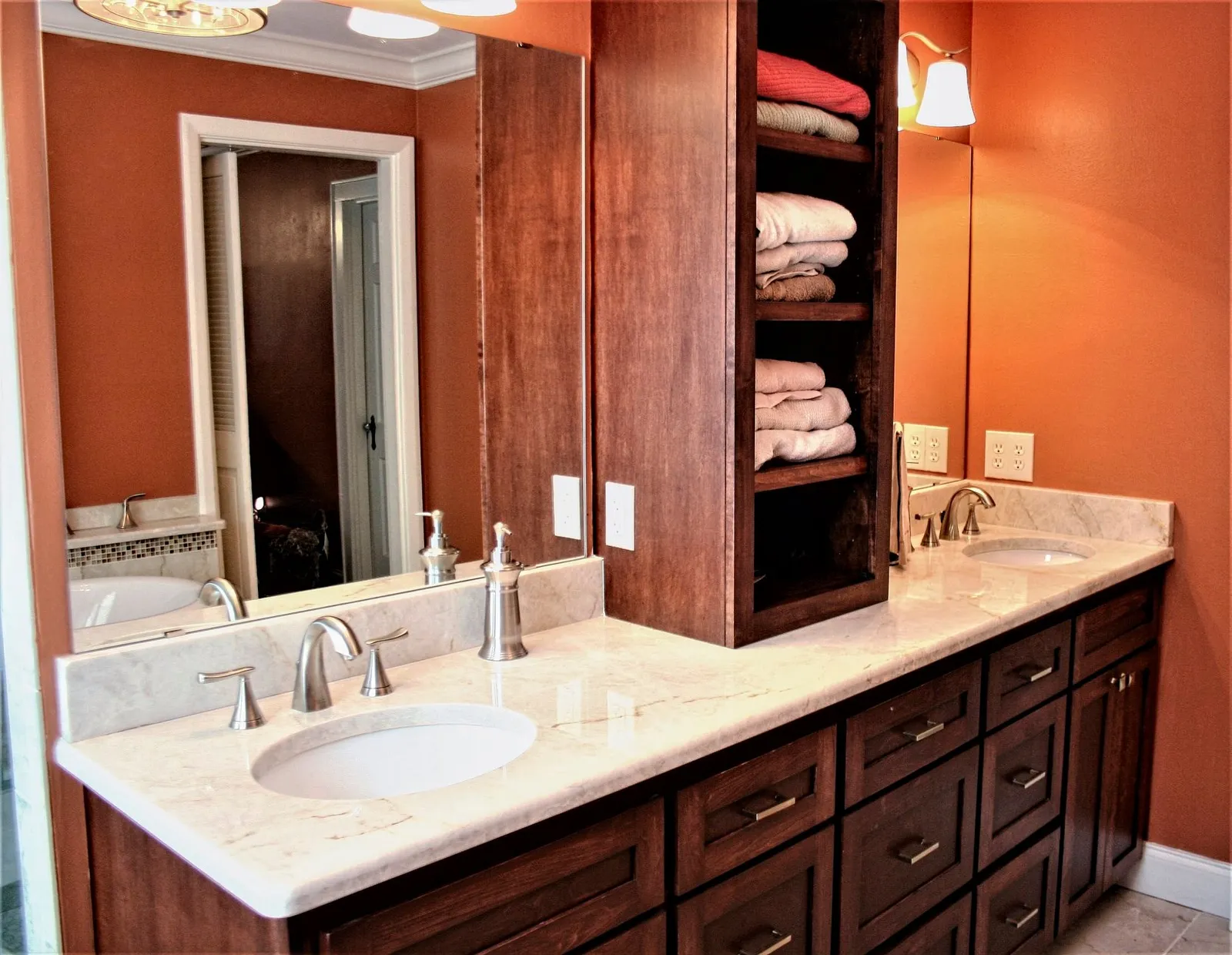 Cherry double vanity with a white marble top and built-in towel shelves.