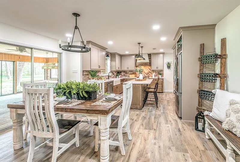 Open kitchen and dining area with wood-look tile floors and a farmhouse table.