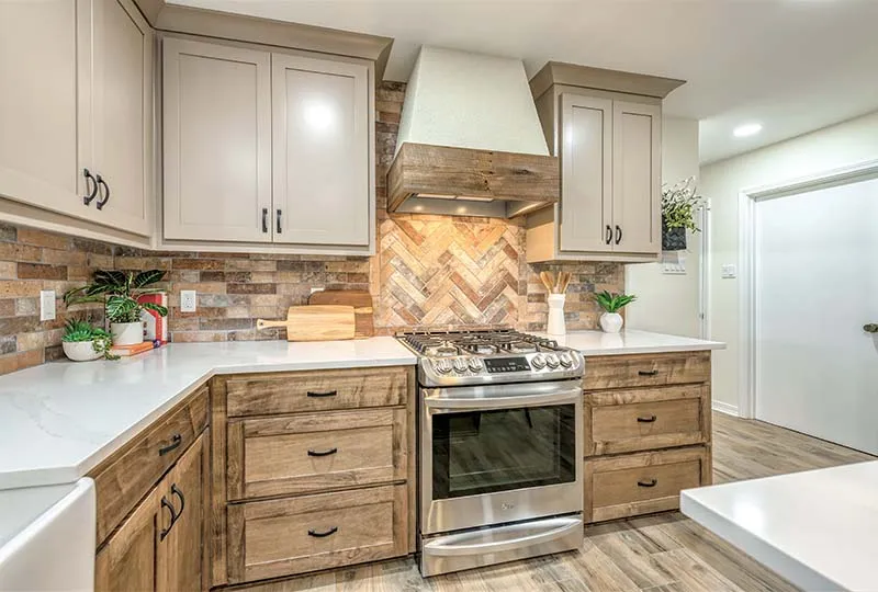 Range under a white hood with a herringbone brick-look tile backsplash.