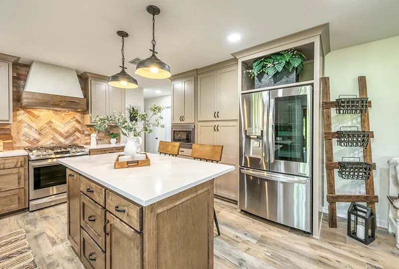 Wood-stained island with a white countertop in front of the herringbone backsplash.
