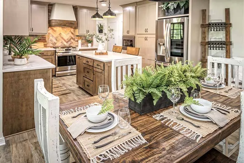 Dining table set for a meal, with the kitchen beyond.