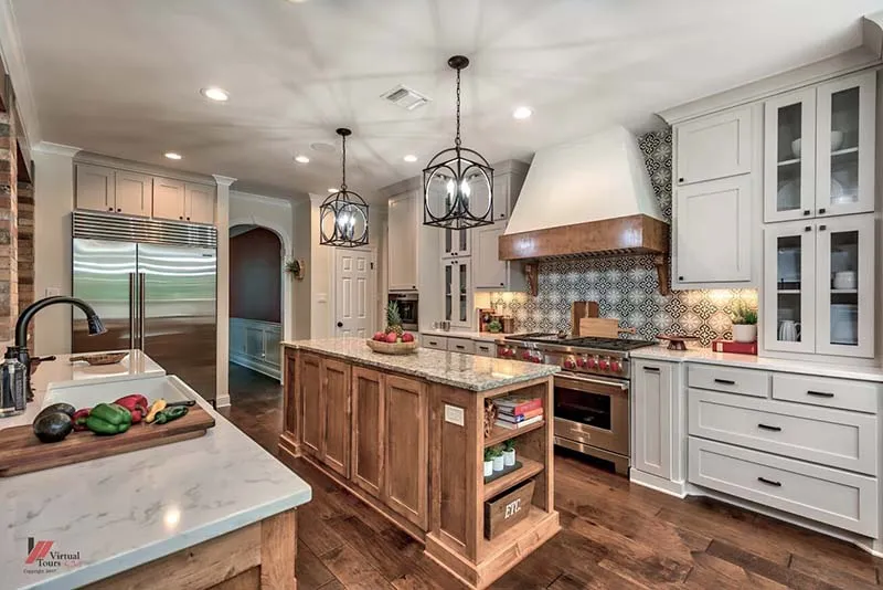 Wood island with granite countertop and gray cabinetry on wood floors.