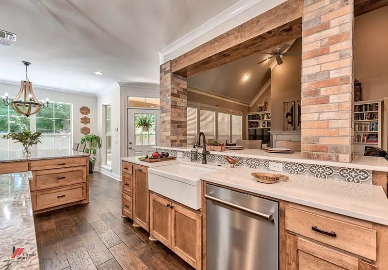Farmhouse sink in a wood island, with brick-look tile columns beyond.