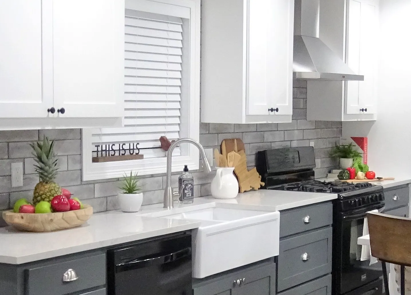 Farmhouse sink set in white quartz with a gray brick-look backsplash.