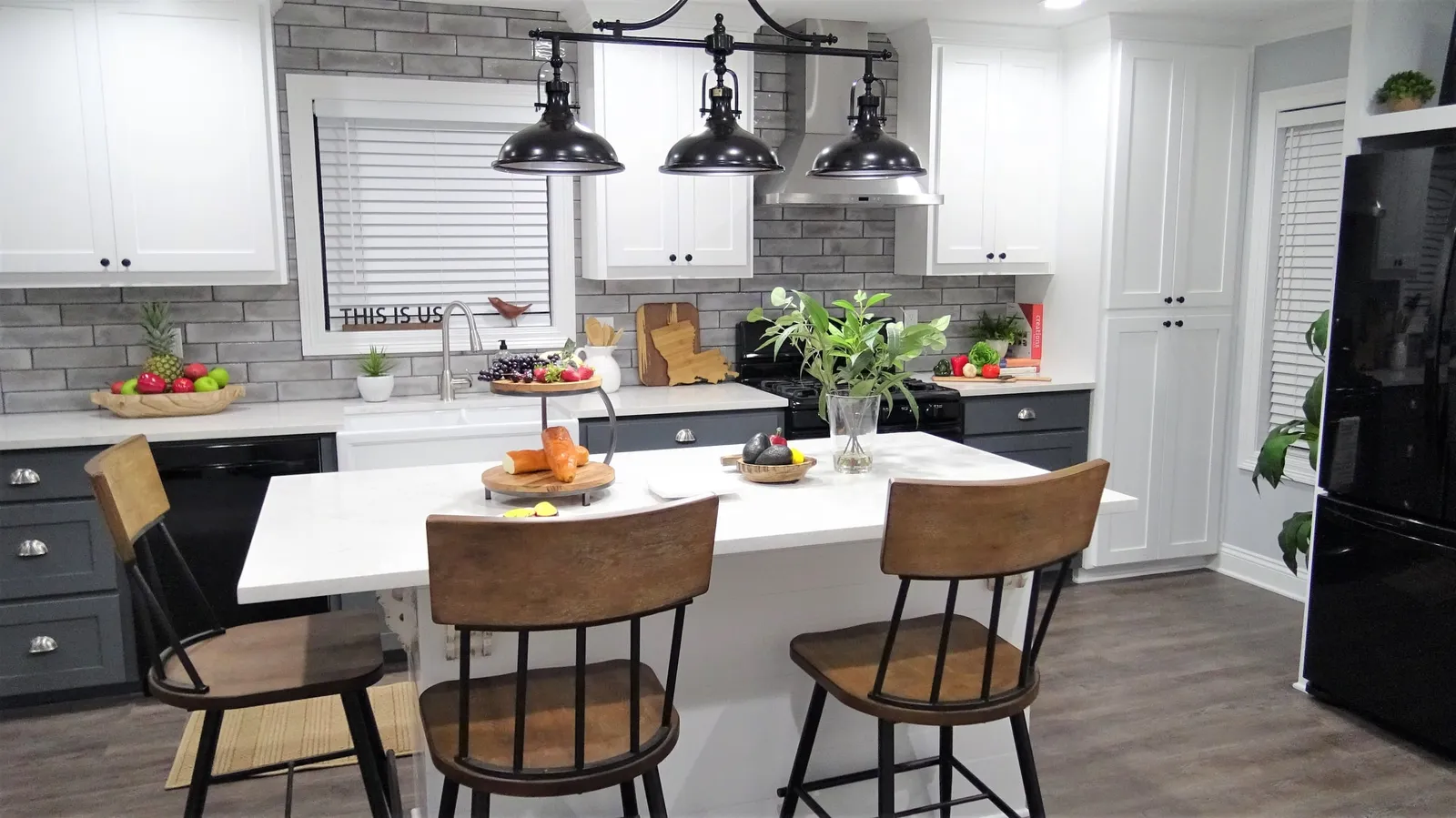 Kitchen island with wood stools under black pendant lights.