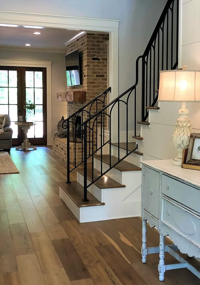 Entry with light engineered hardwood floors and a black iron stair railing.