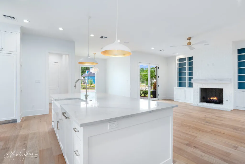 Kitchen island with a quartzite countertop, open to the living room and its light wood floors.