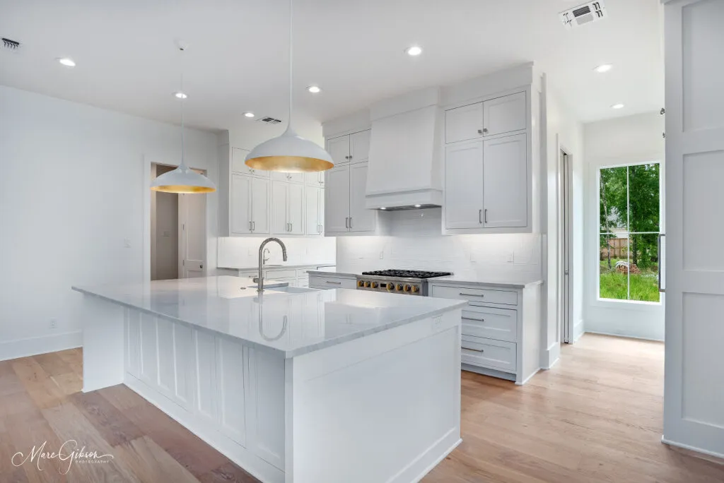 Quartzite countertop on a white kitchen island, with the range and cabinets behind it.