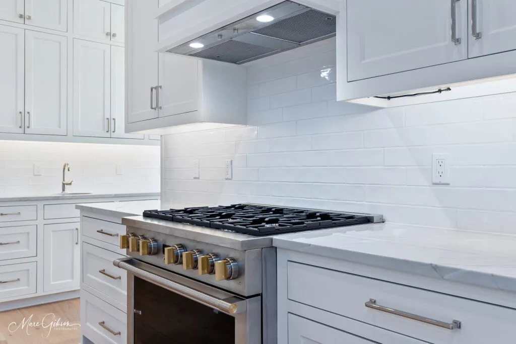 Gas range between quartzite countertops, with a white subway tile backsplash.